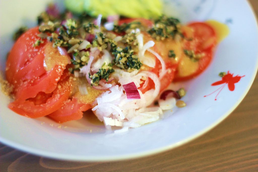 Salade de tomates coeur de boeuf, vinaigrette maison, pesto maison basilic/graines de tournesol, oignons nouveaux et gomasio.