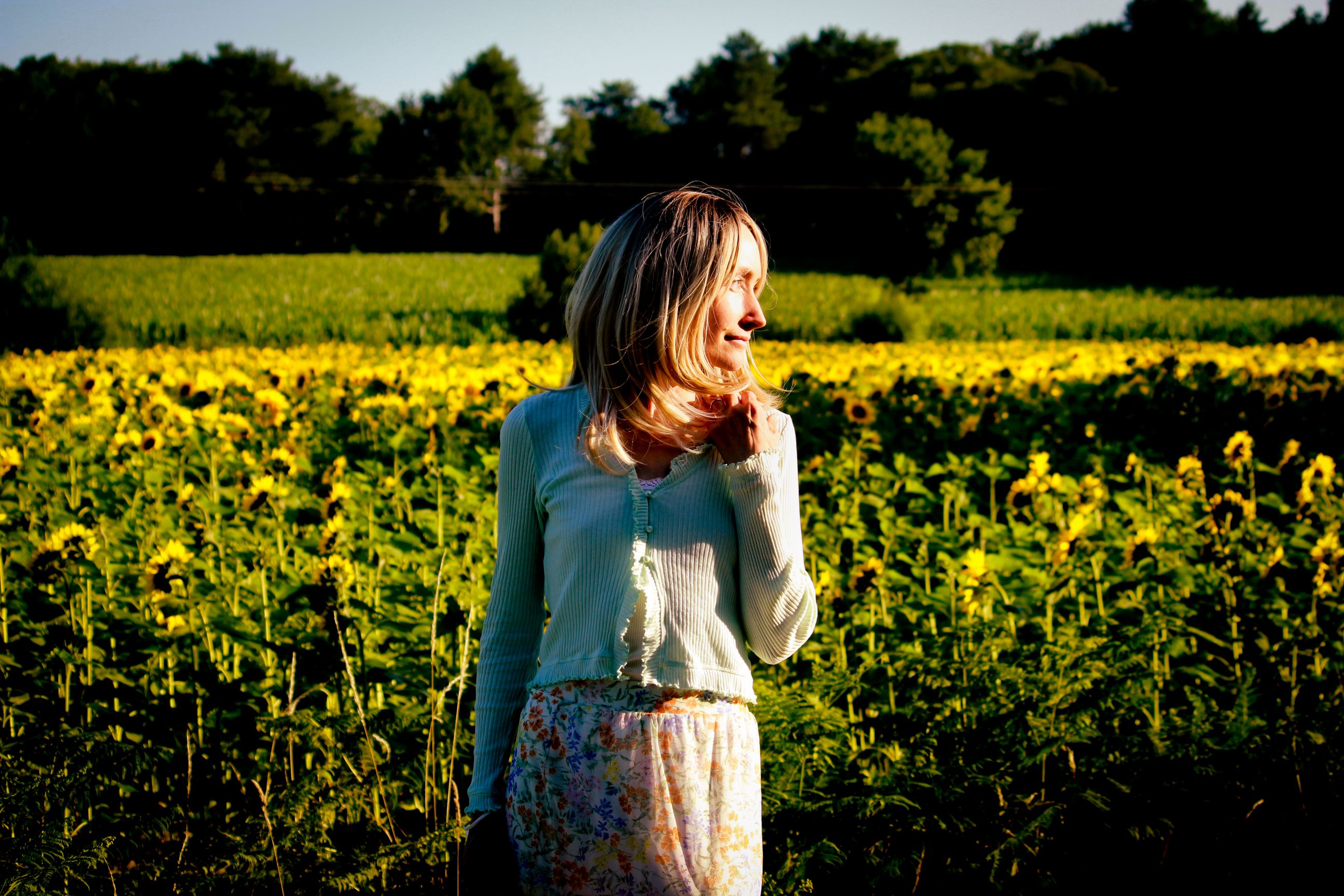 Femme blonde qui porte une jupe longue dans un champ de tournesols